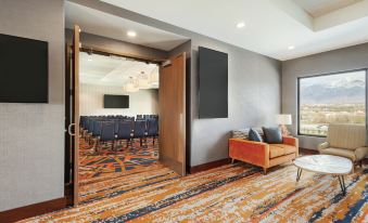 a room with a couch , chairs , and a tv is shown with an orange and gray carpet at Embassy Suites by Hilton South Jordan Salt Lake City