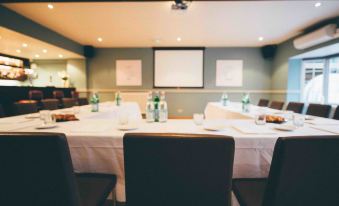 a conference room with a table set up for a meeting , featuring white tablecloths and chairs at The Blue Boar