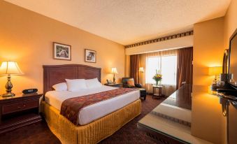 a large bed with a brown headboard and gold accents is in a hotel room at Cherokee Casino West Siloam Springs Resort