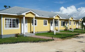 a row of yellow houses with white trim , situated next to each other on a dirt road at Country Cove