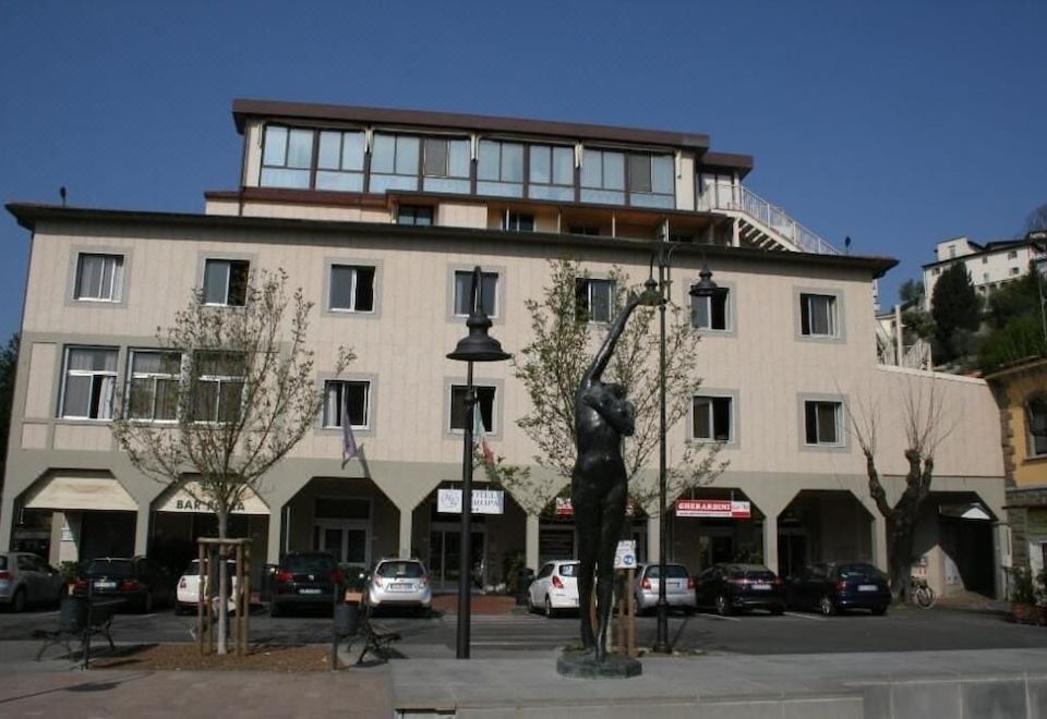 a building with a statue of a woman in front , surrounded by cars and other buildings at Hotel Europa