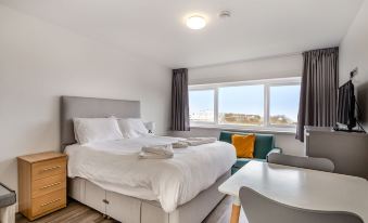 a hotel room with a large bed , a desk , and a window overlooking the ocean at North Devon Resort