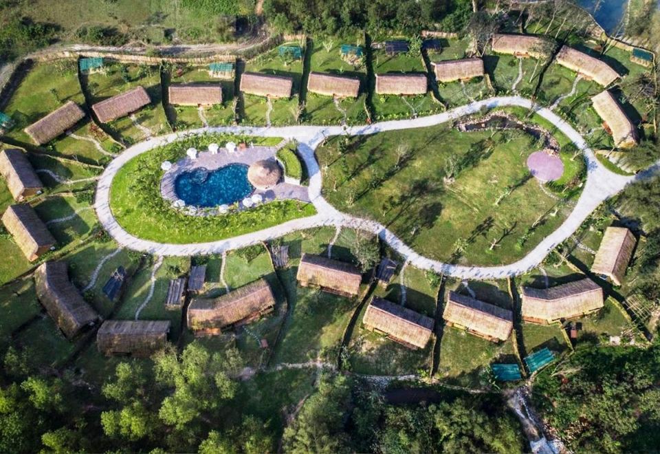 an aerial view of a residential area with a circular pool surrounded by green grass and trees at Alba Wellness Resort by Fusion