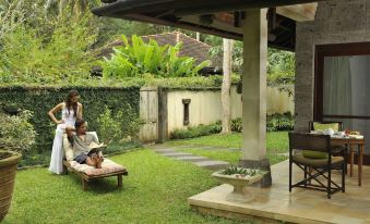 a group of people , including a man and a woman , are sitting on chairs in a lush green backyard at The Farm at San Benito
