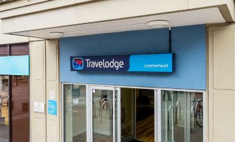 the entrance to the travelodge hotel with a blue sign and a wooden door at Travelodge Leatherhead