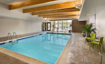 an indoor swimming pool with a large window , surrounded by stone walls and wooden beams at Home2 Suites by Hilton Downingtown Exton Route 30