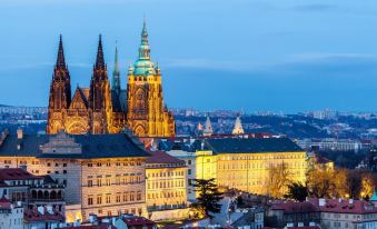 a city skyline at dusk , with the hradcany castle in prague illuminated against a blue sky at Pure White