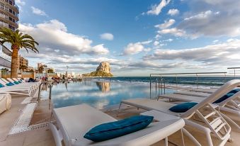 a large outdoor pool surrounded by lounge chairs , with a view of the ocean in the background at Solymar Gran Hotel