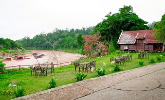 a serene outdoor setting with a gazebo , grassy area , and a lake , accompanied by a house and a boat at Mutiara Taman Negara