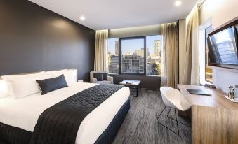 a modern hotel room with a large window offering a view of the city , a comfortable bed , and modern furniture at Hotel Grand Chancellor Brisbane