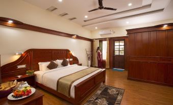a large bed with a wooden headboard is in a room with a woman standing near the door at Coorg Cliffs Resort
