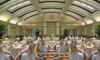 a large , well - lit banquet hall with tables set up for a formal event , including white tablecloths , napkins , and at Hilton Garden Inn Jackson Downtown