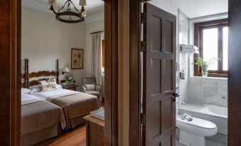 a bedroom with a bed , nightstands , and chairs is shown through an open door leading to a bathroom at Parador de Gredos
