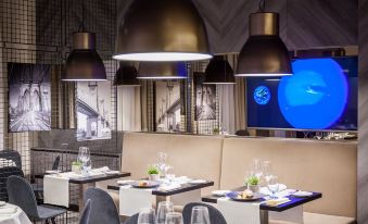a modern restaurant with black tables , chairs , and lamps , creating an inviting atmosphere for diners at Galaxy Hotel