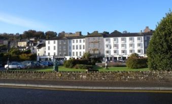 a large white building with a gray facade and many windows is surrounded by trees and grass at Actons Hotel Kinsale