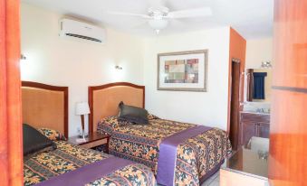 a hotel room with two beds , a fan , and a painting on the wall , all neatly arranged at Cactus Inn Los Cabos