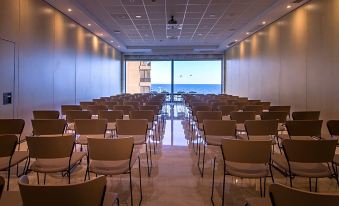 a large conference room with rows of chairs arranged in a semicircle , facing a large window overlooking the ocean at Solymar Gran Hotel
