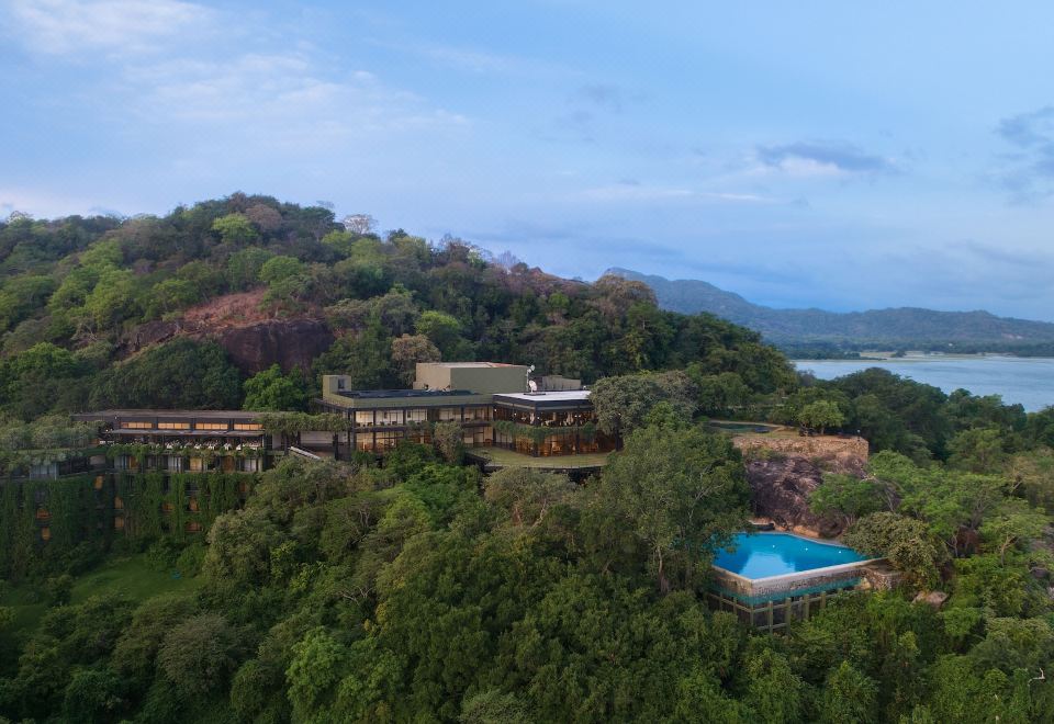 aerial view of a resort surrounded by trees and mountains , with a swimming pool in the foreground at Heritance Kandalama