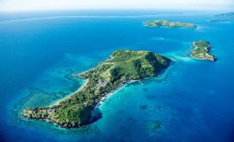 aerial view of a tropical island with lush green vegetation , clear blue water , and white sandy beaches at Kokomo Private Island Fiji