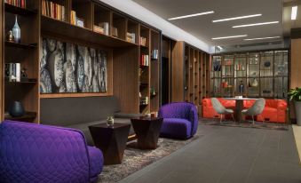 a modern living room with purple couches , wooden walls , and a dining area in the background at Hyatt Centric Arlington