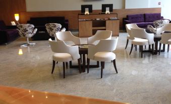 a modern , well - lit lobby with white couches and chairs arranged around a coffee table , creating a comfortable and inviting atmosphere at Hotel Principe
