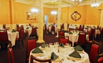 a well - decorated banquet hall with multiple tables set for dining , each table having its own green place mats at Hotel Coolidge