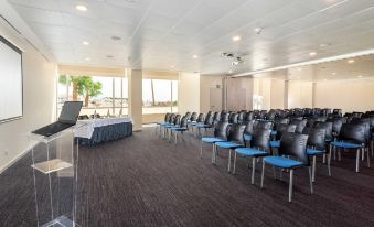 a large conference room with rows of chairs arranged in a semicircle , and a podium at the front of the room at AP Maria Nova Lounge