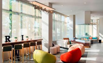 a modern hotel lobby with a large window , wooden ceiling , and several colorful bean bag chairs arranged around the seating area at Residence Inn by Marriott Boston Watertown
