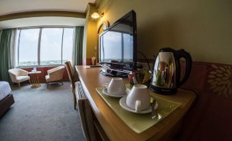 a hotel room with a television , kettle , and cups on a table near the window at Chaisaeng Palace Hotel