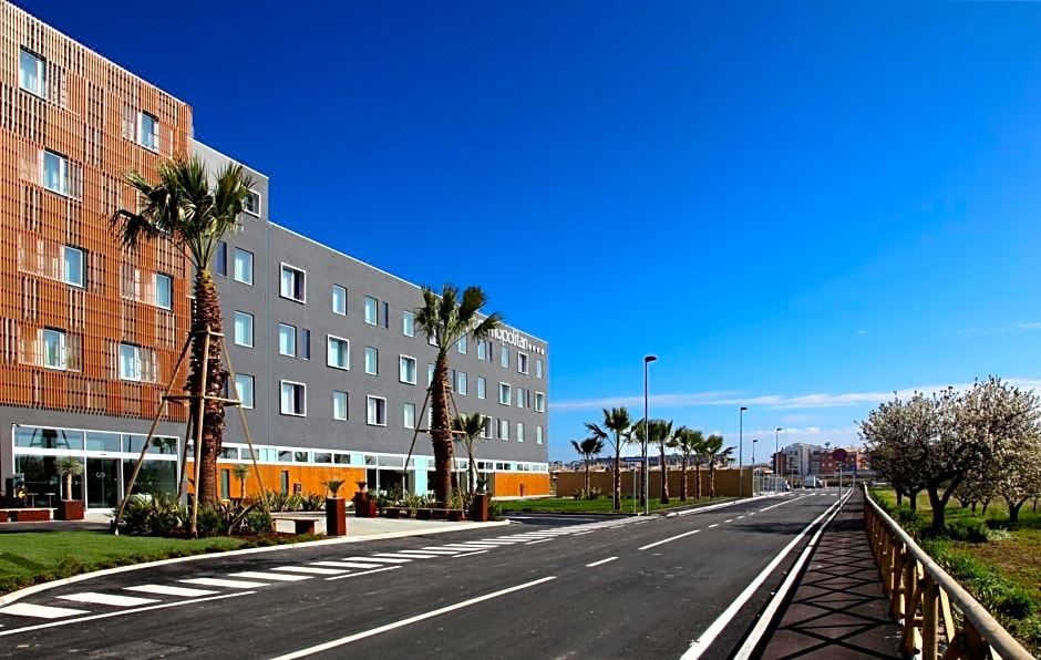 a modern , gray and white building with palm trees on the side , under a clear blue sky at Cosmopolitan Hotel