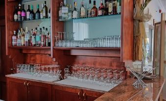 a wooden bar with multiple bottles and glasses on the counter , along with a marble countertop at Hotel President