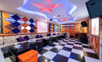 a brightly lit room with black and white checkered flooring , purple and orange pillows , and a colorful star ceiling at Lbn Asian Hotel