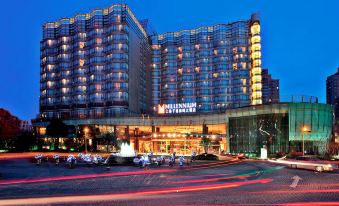 A large building with an illuminated hotel in front, offering a view of the outside at night at Grand Millennium Shanghai HongQiao