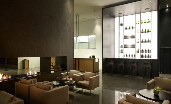 a modern lounge area with beige couches and chairs , a bar area , and shelves filled with wine bottles at Shilla Stay Dongtan