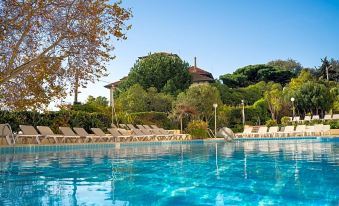 a large swimming pool with lounge chairs and a villa in the background , under a clear blue sky at Hotel Estoril Eden