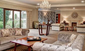 a luxurious living room with elegant furniture , including couches , chairs , and a coffee table , under a chandelier at Best Western Plus Centurion Hotel