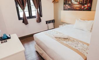 a neatly made bed with white linens is situated in a room with brown curtains and a painting on the wall at Kertih Damansara Inn