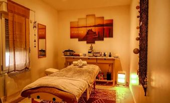 a dimly lit room with a massage table and a painting on the wall , creating a relaxing atmosphere at La Bastide