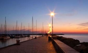 a paved walkway leading to a marina at sunset , with numerous boats docked in the water at Hotel Europa
