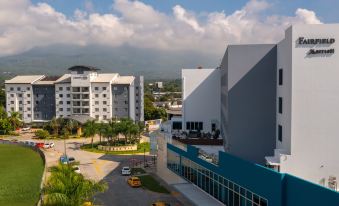 a city skyline with a large white building in the foreground , surrounded by other buildings and trees at Fairfield by Marriott San Salvador