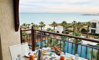 a table with a variety of food and drinks is set on a balcony overlooking the ocean at Four Seasons Hotel Tunis