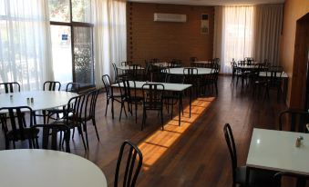 a large , empty room with wooden floors and walls , containing several tables and chairs arranged around them at Discovery Parks - Port Augusta