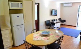 a small apartment with a dining table and chairs , a refrigerator , and a microwave in the corner at Dolphin Lodge Albany - Self Contained Apartments at Middleton Beach
