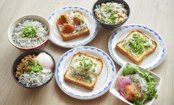 a dining table with a variety of food items , including sandwiches , bowls of rice , and a variety of side dishes at Sotetsu Fresa Inn Kamakura-Ofuna Higashiguchi