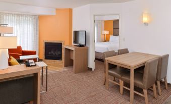 a modern hotel room with an orange and white color scheme , featuring a desk , chairs , and a television at Residence Inn Palo Alto Los Altos