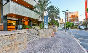 a hotel entrance with a sign , palm trees , and a stone walkway in front of it at San Marino Suites Hotel by Nobile