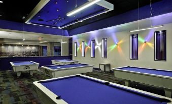 a room with multiple pool tables and chairs , illuminated by colorful lights , creating a bright and inviting atmosphere at Costa Bahia Hotel, Convention Center and Casino