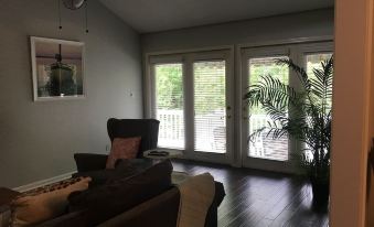 a living room with a couch , chair , and potted plant in front of sliding glass doors at The Waterford