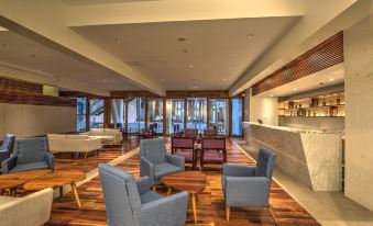 a modern lounge area with blue chairs , wooden tables , and a bar in the background at Hotel Somadevi Angkor Resort & Spa