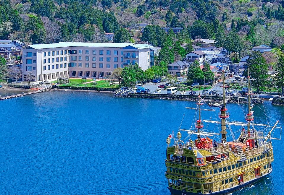 a large yellow and red ferry boat is sailing in a body of water near a hotel at Hakone Hotel